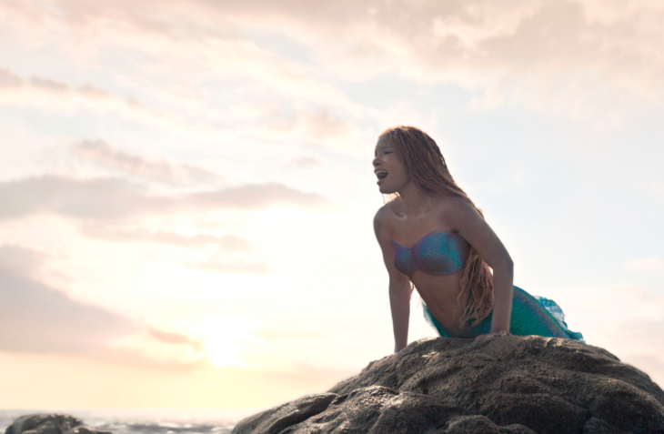 imagen de la película La Sirenita donde Ariel está apoyada sobre una piedra cantando
