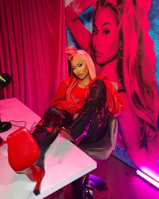 Nicki Minaj sentada en una silla con un pie sobre el escritorio 