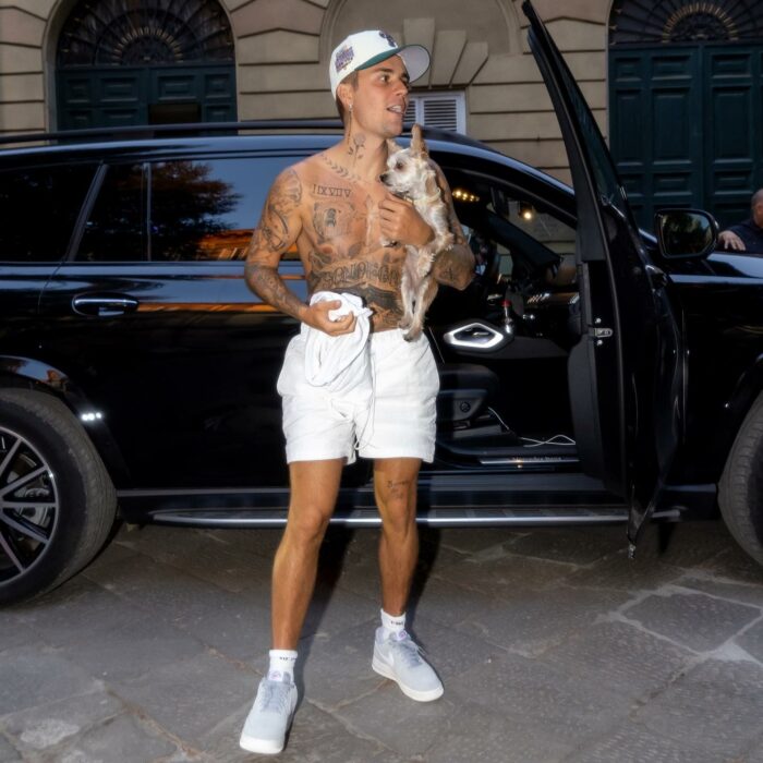 Justin Bieber posando sin camisa en short frente a una camioneta 