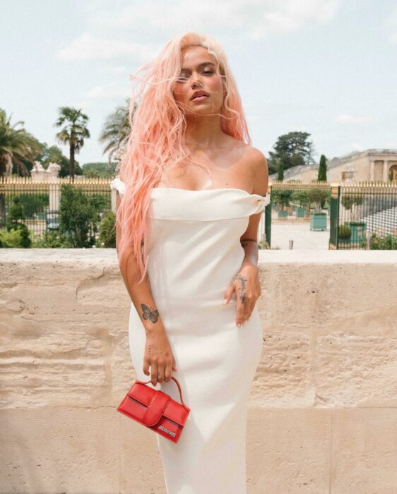 Karol G posando con un vestido blanco afuera del Palacio de Versalles 