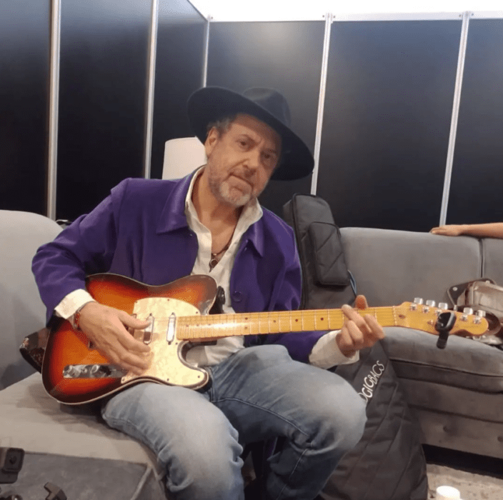 El exguitarrista de Caifanes Alejandro Marcovich sentado en un sofá con su guitarra en las piernas