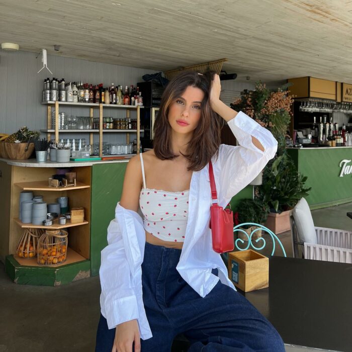 Fotografía de una chica dentro de una cafetería posando con la mano en la cabeza 