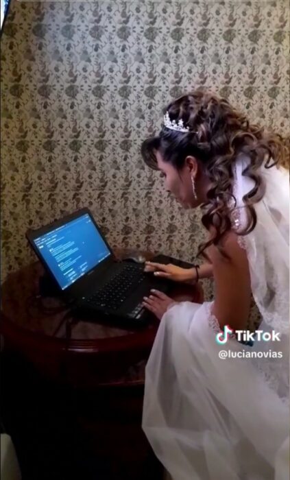 Mujer vestida de novia enviando una tarea de su maestría antes de su boda 