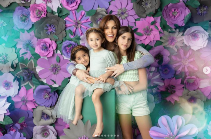 Natalia Alcocer en una sesión de fotos juntos a sus tres hijas rodeadas de flores violetas 