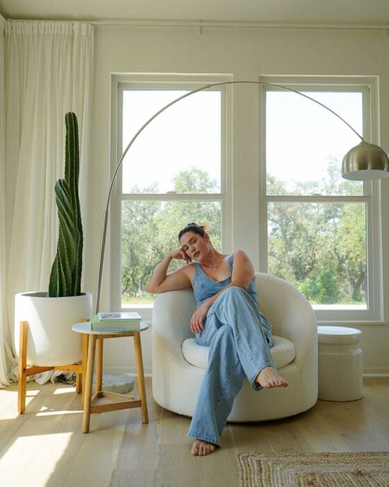 Fotografía de una mujer sentada en un sofá cerca de la ventana de una casa 