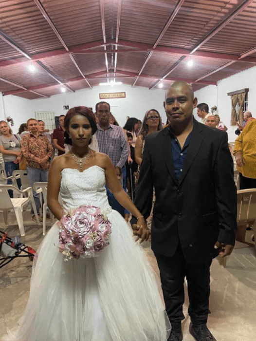 una pareja de novios tomados de la mano saliendo de la iglesia de un pueblo mexicano