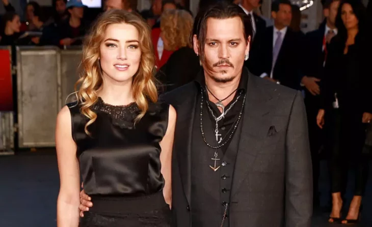 Johnny Deep posa abrazando a Amber Heard ambos van vestido de negro