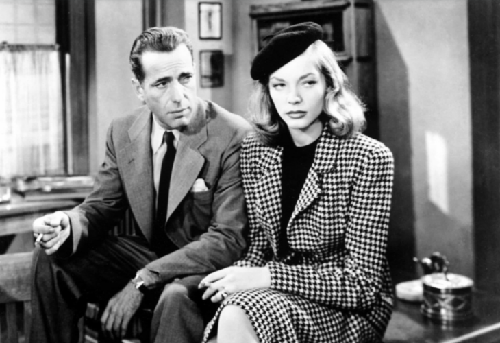 Humphrey Bogart sentado junto a su coprotagonista Lauren Bacall en una escena de la película Tener y no tener