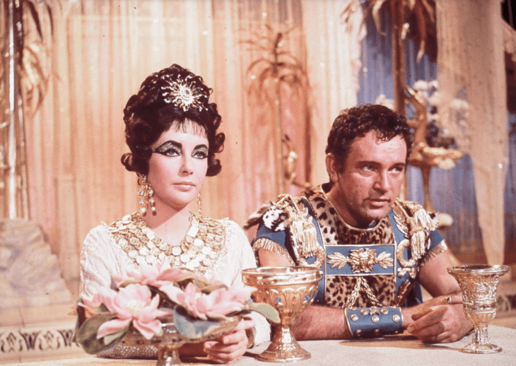  Elizabeth Taylor y Richard Burton caracterizados con sus personajes de la película de Cleopatra están sentados a la mesa en el set de filmación