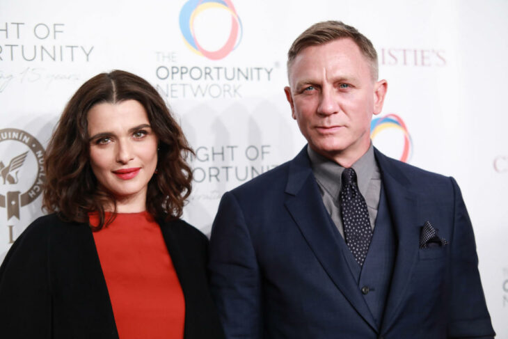 Rachel Weisz y Daniel Craig posan sonrientes en la alfombra roja de algún evento llevan ropa semiformal 