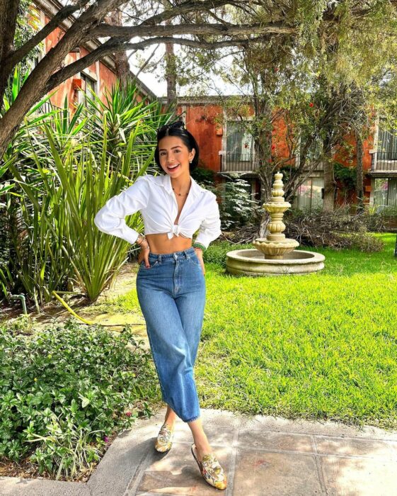 Ángela Aguilar en un jardín con una fuente 