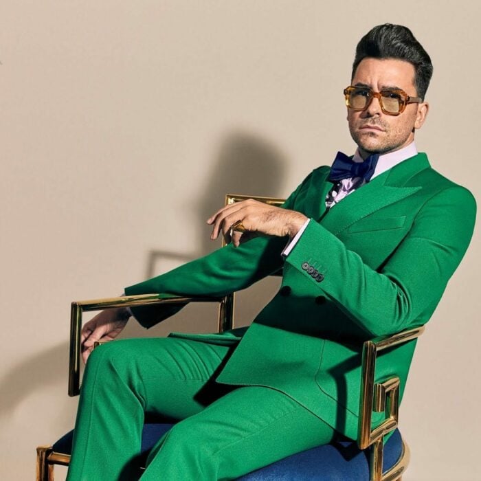 Dan Levy sentado con un traje sastre color verde 