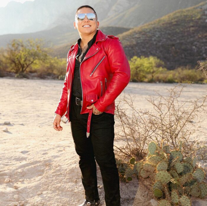 Edwin Luna con chamarra roja y vestido todo de negro 