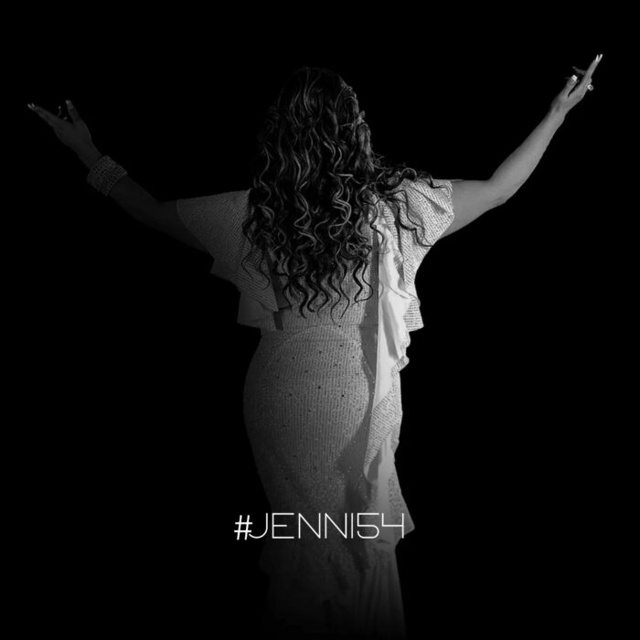 Jenni rivera de espaldas con las manos abiertas en foto en blanco y negro 