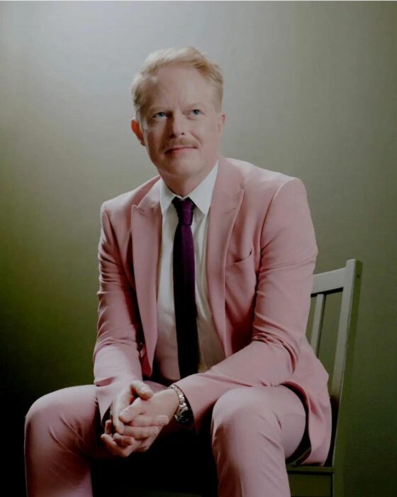 Jesse Tyler Ferguson sentado con traje sastre de color rosa 