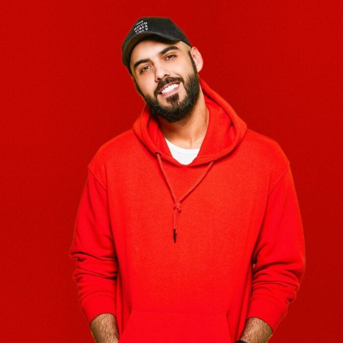 Omar borkan con sudadera roja fondo rojo y gorra negra 