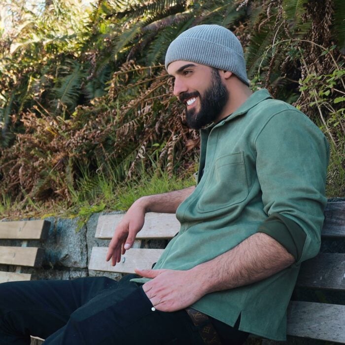 Omar Borkan con gorra de perfil y sentado en una banca 