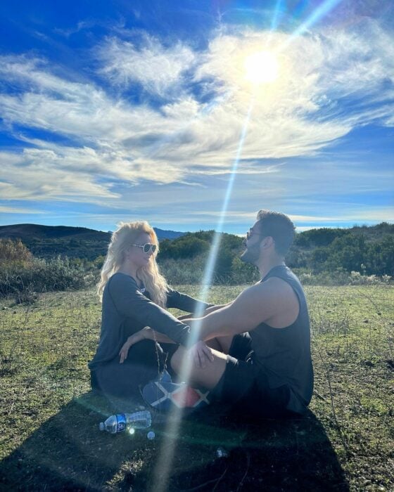 Sam y Britney sentados en el pasto con la luz del sol 