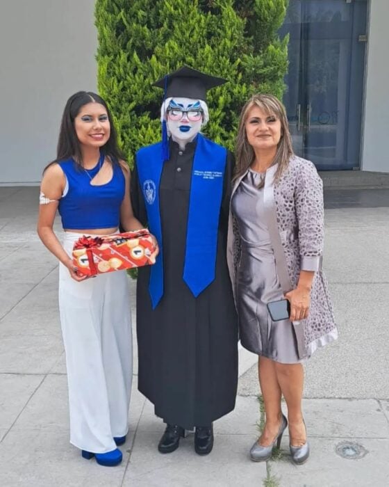 Shirley Méndez Alderete vestida como trans en su graduación acompañada de dos mujeres