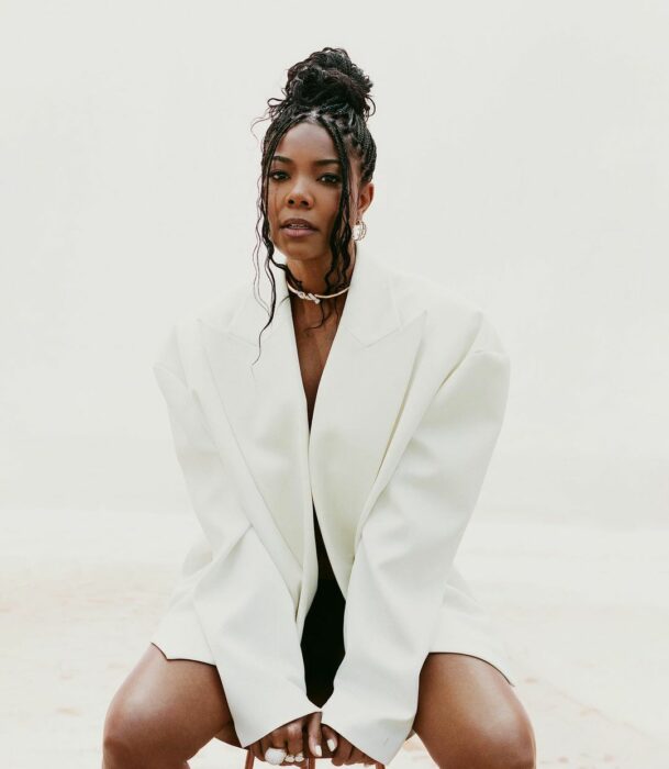 Gabrielle Union con saco blanco sentada con las piernas abiertas