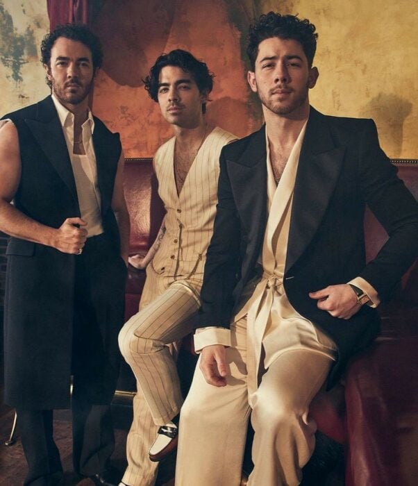 Los Jonas Brothers posando para foto recargados en muebles 