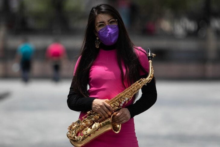 Elena Rios con su sax y vestido rosa en medio de una plaza