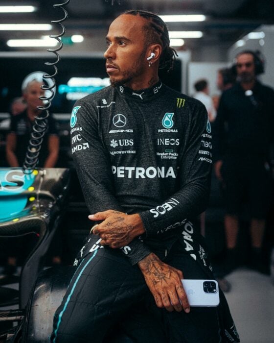 Lewis Hamilton posando recargado en uno de sus carros en una carrera 