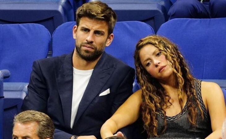 Shakira y Gerard Piqué sentados en los asientos de un estadio deportivo ella luce triste y él algo enfadado