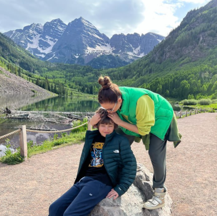 Thalía agachada besa en la cabeza a su hijo menor Matthew quien está sentado en una roca