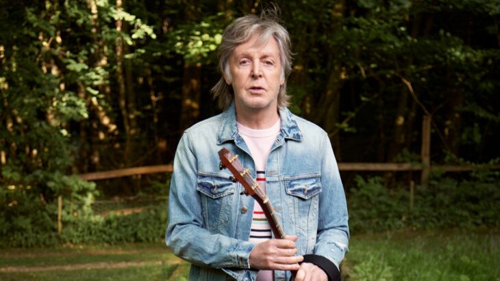 Sir Paul McCartney posa en un jardín con ropa casual lleva en las manos una guitarra