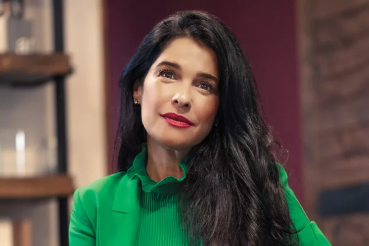 Martha Debayle posa con cara de sorpresa lleva vestimenta color verde y el cabello suelto peinado en ondas 