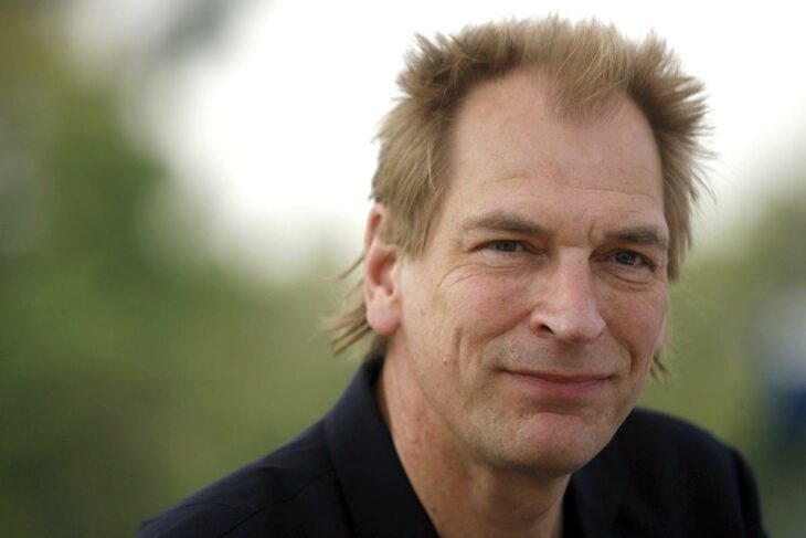 Julian Sands en exterior con camisa negra 