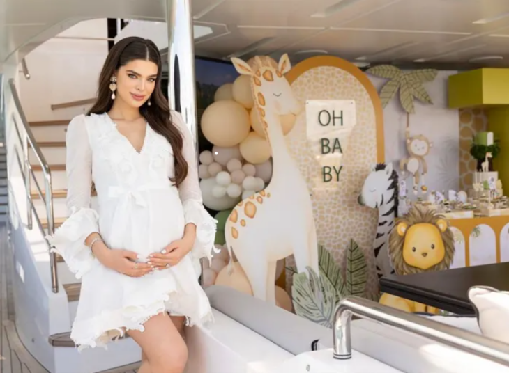 Nadia Ferreira posa sonriente con un vestido blanco mostrando orgullosa su pancita en el interior de un yate donde celebró su baby shower 