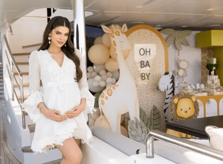 Nadia Ferreira posa sonriente con un vestido blanco mostrando orgullosa su pancita en el interior de un yate donde celebró su baby shower 