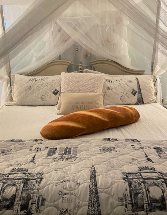 un baguette enorme puesto sobre una cama con decoración parisina