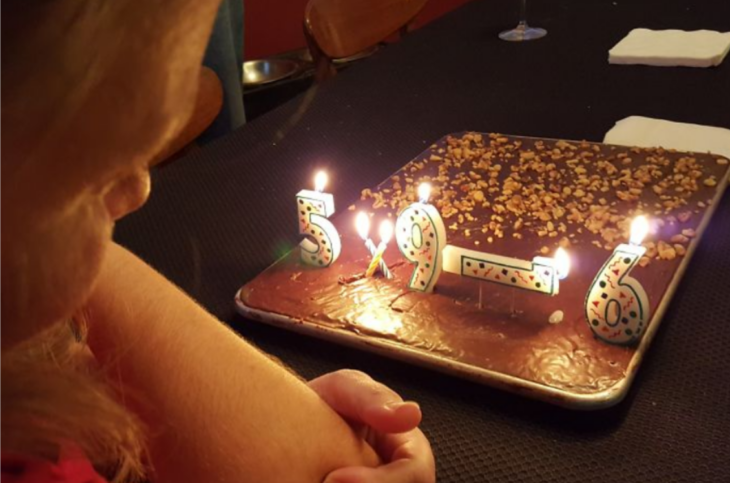 un pastel con velas de cumpleaños encendidas una chica espera para soplarles