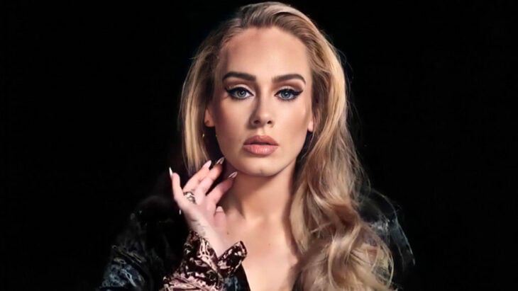 Adele posa con elegancia mirando fijamente a la cámara lleva las uñas largas y pintadas y el cabello suelto 