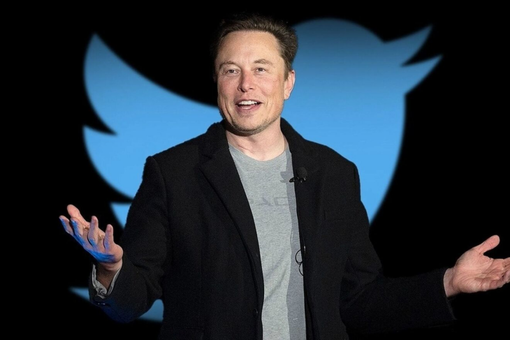 Elon Musk posando frente a un emoji de Twitter 