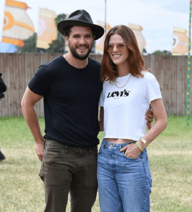 Kit Harington y Rose Leslie posan sonriendo con ropa casual en el jardín de una casa él lleva un sombrero de gamuza negro