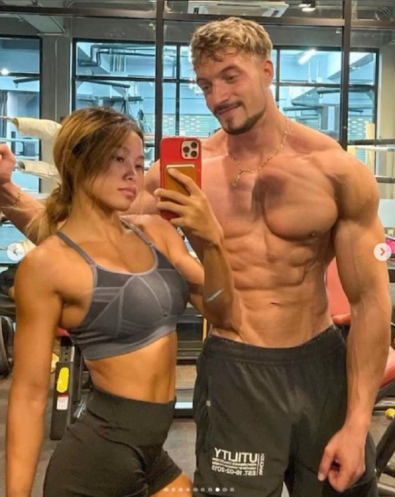 pareja de fisiculturistas posan frente al espejo para una selfie están en un gimnasio y llevan ropa deportiva 