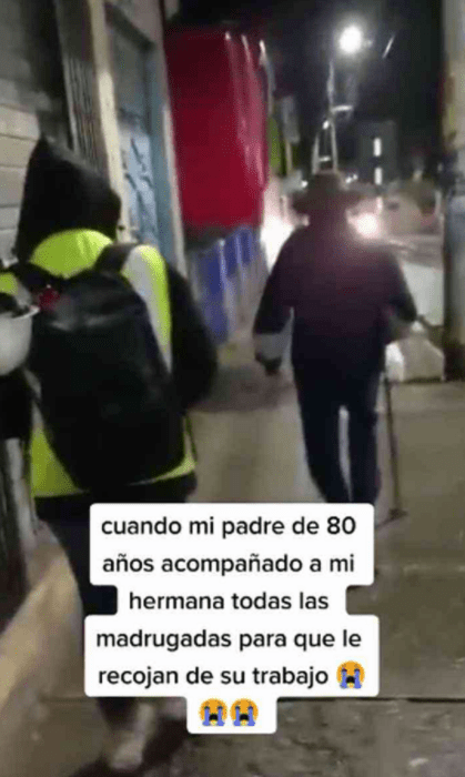 un hombre mayor camina al frente de una mujer por las calles de una ciudad aluzada con la luz artificial