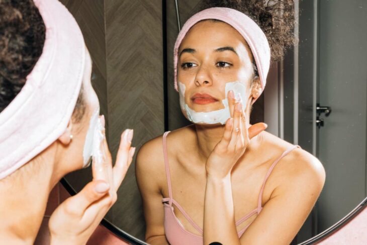 Mujer morena haciendo su skincare aplicándose mascarilla en la cara 