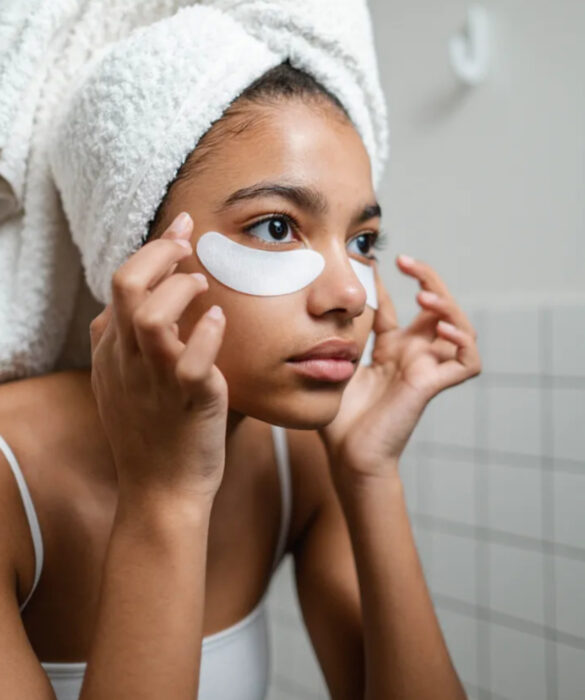 Adolescente morena haciendo rutina de skincare con parches para los ojos