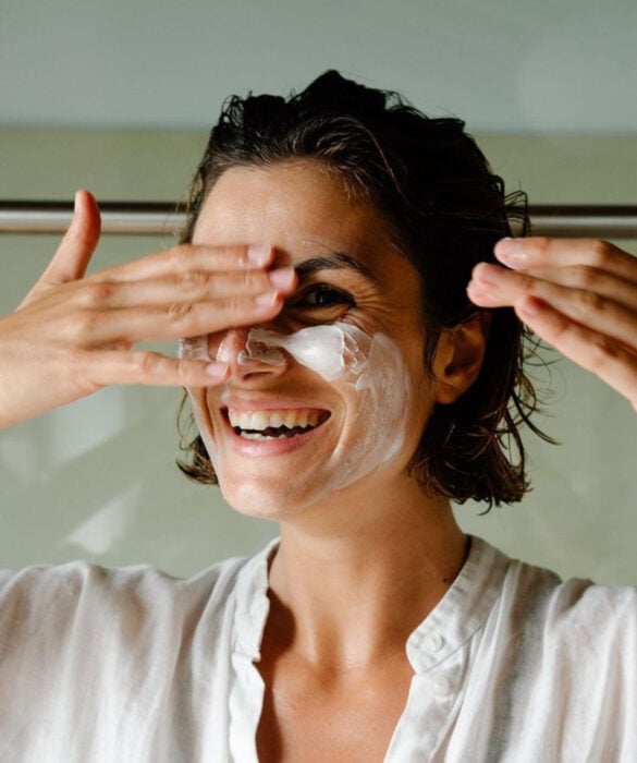 Mujer haciendo skincare y poniéndose crema en el rostro