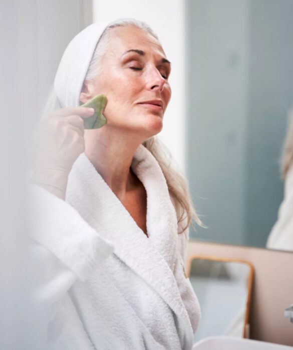 Mujer mayor haciendo rutina de skincare y usando gua sha